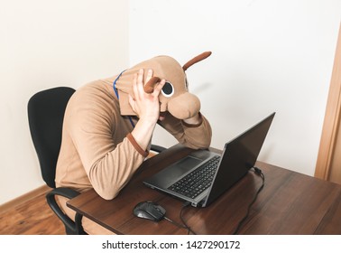 Office Worker In Cosplay Costume Of A Cow. Guy In The Funny Animal Pyjamas Sleepwear Near The Laptop. Parody On Desperate Manager. Occupational Burnout.