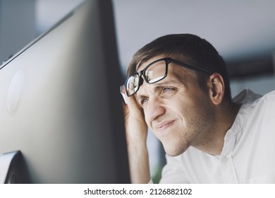Office worker with eyesight problem, he is trying to focus on the computer screen