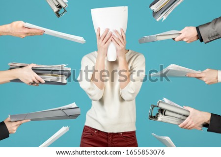 an office worker hid behind a document, and at this time, colleagues and managers were handing him more and more new work. Office worker overworked