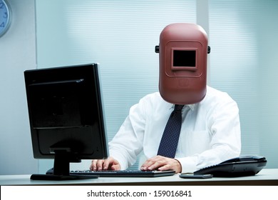 An office worker at his desk wearing a welder's mask