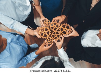 Office worker holding cog wheel as unity and teamwork in corporate workplace concept. Diverse colleague business people showing symbol of visionary system and mechanism for business success. Concord - Powered by Shutterstock