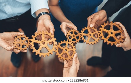 Office worker holding cog wheel as unity and teamwork in corporate workplace concept. Diverse colleague business people showing symbol of visionary system and mechanism for business success. Concord