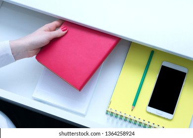 Office worker holding a red notebook, Desk, smart phone, open shelf, female hand, close up, top view, background, copy space, advertising
