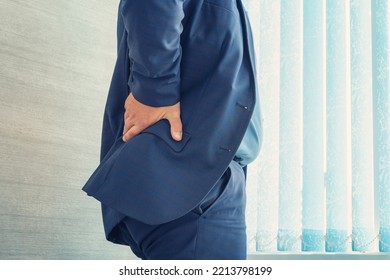 Office Worker Holds His Hand Over His Sore Back. Health Problems From Sedentary Work. Casual Businessman Touching His Sore Back In His Office