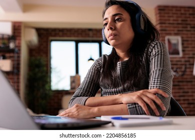 Office Worker Listening To Music On Headphones And Working On Report With Laptop At Home. Doing Remote Work Job And Enjoying Podcast Or Song, Attending Online Class Webinar On Computer.