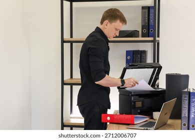 Office worker positioning sheet inside open scanner on desk with binders and computer