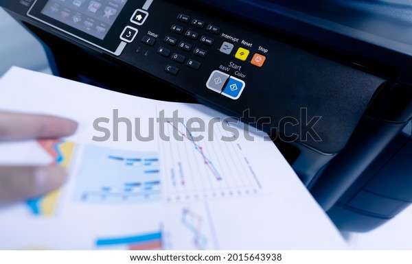 Office worker print paper on multifunction laser
printer. Copy, print, scan, and fax machine in office. Modern print
technology.  Photocopy machine. Document and paper work. Scanner.
Secretary work.