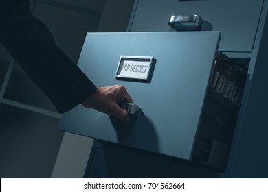 Office worker searching top secret confidential information in the office late at night, data theft and security concept