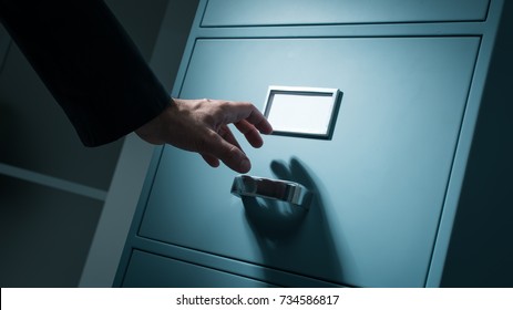 Office worker searching top secret confidential information in the office late at night, data theft and security concept
