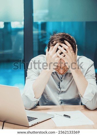 Office worker sits at table and holds his head in his hands. Depression and crisis in workplace. Oppressed worker. Portrait of depressed and frustrated analyst.