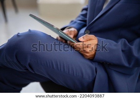 Office worker sitting and using tablet. Close-up shot of tablet. Male employee in official suit working in office using gadget. Business, technology, connection, internet concept
