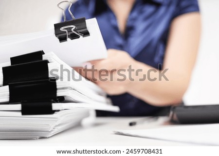 An office worker sorts out a stack of papers fastened with Binder Clips