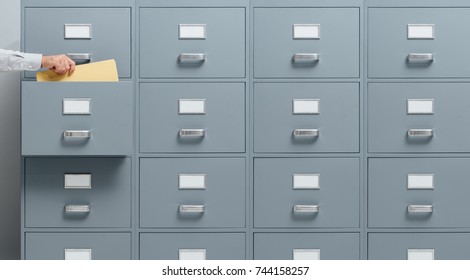 Office Worker Taking A File From A Filing Cabinet Drawer, Business And Administration Concept