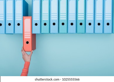 Office worker taking an highlighted folder in the archive: database, administration and file management concept - Shutterstock ID 1025555566