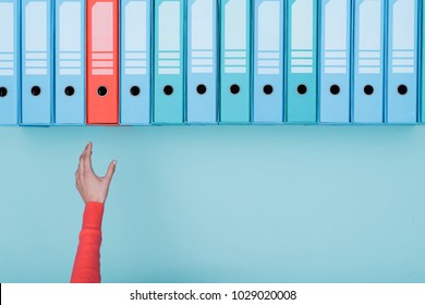 Office worker taking an highlighted folder in the archive: database, administration and file management concept - Powered by Shutterstock