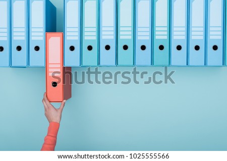 Office worker taking an highlighted folder in the archive: database, administration and file management concept