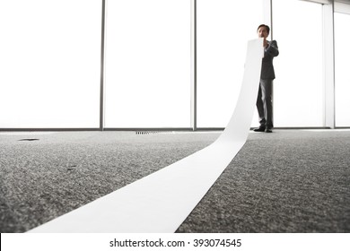 Office Worker Unrolling Long Sheet Of Paper