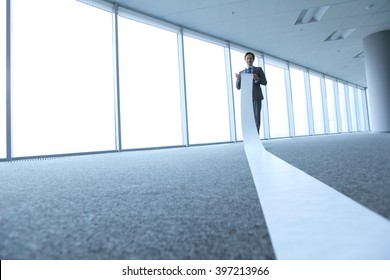 Office Worker Unrolling Long Sheet Of Paper