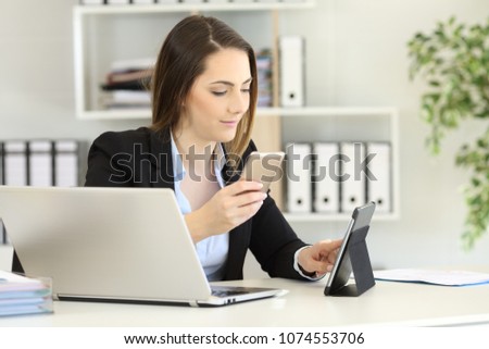 Office worker working with multiple devices on a desktop