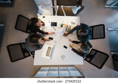 Office workers gather around a table to do research and implement new ideas. High angle view of multi-ethnic business people discussing in board room meeting