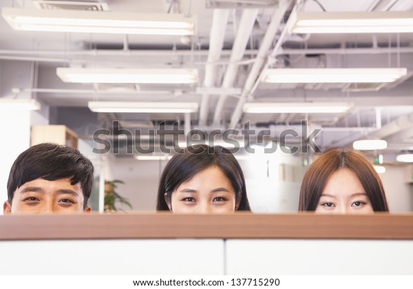 Office workers\
peeking over divider in\
office