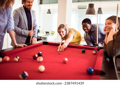 Office workers playing pool together. Young man and woman playing billiards after work - Powered by Shutterstock