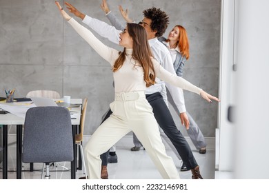 Office workers workout during coffee break. They try to exercise and practice yoga to relax before working day. - Powered by Shutterstock