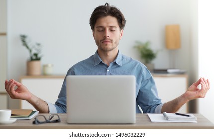 Office Zen. Relaxed Young Man Meditating Sitting At Laptop Computer At Workplace.