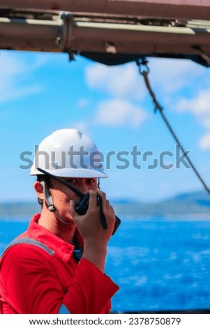 an officer on duty is communicating via walkie-talkies or radio while carrying out a cargo operation. seafarer using full personal protective equipment. concept communication