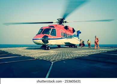 The officer take care passenger to embark helicopter at oil rig platform
