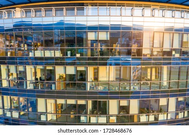 Offices In A Modern High Rise Commercial Building With Glass Facade. Sunset Reflecting Off The Exterior Of A Corporate Headquarters With Suites For Rent.