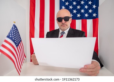 Official Letter In Hands Of Man From America. Concept - Official Letter From US Government Agencies. American Flag Behind A Man. Human Reads An Official Letter From Government US . State Gov Message