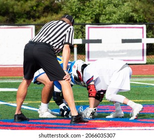 An official is standing over two high school boys during the face off of a lacrosse gane on a furf field close up. - Powered by Shutterstock