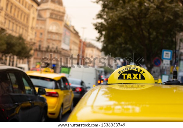 Official taxi service of\
the city of Budapest, characterized by its yellow color and black\
checkered band