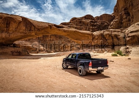 Off-road car near the rock arch in Wadi Rum desert. Jordan