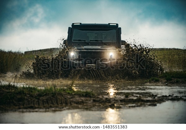 Offroad car on bad road. Off road jeep expedition to\
the villages on mountain road. Mud and water splash in off-road\
racing. Offroad car