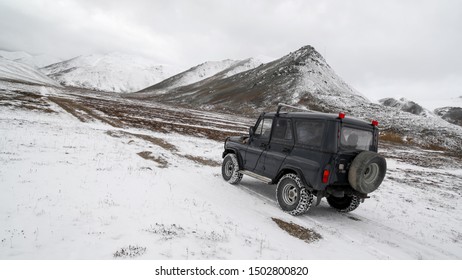 Off-road Car Rides On A Snowy Road In A Valley Among The Mountains Near The Intersection Of The Arctic Circle And The 180th Meridian. Chukotka, Russia. Expeditions, Arctic Travel And Extreme Tourism.