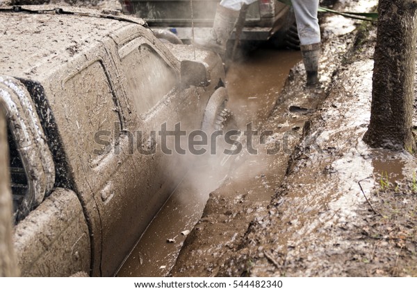 Off-road\
mud vehicle at the forest. Off-road car going through deep mud\
holes. Detail of dirty car with filled mud - carwash concept. car\
wheels. dirty car wheel stands on forest\
road