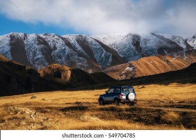 Viagem de estrada off-road em carro na estrada de montanha contra rochas e geleira no Cáucaso, Geórgia. Luzes bonitas e cores ao pôr do sol