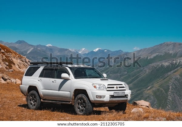 Offroad SUV in mountains. Toyota\
4runner with snowy mountains on background. Off-road journey,\
travel concept. 01.08.2021 Dzungarian Alatau,\
Kazakhstan.