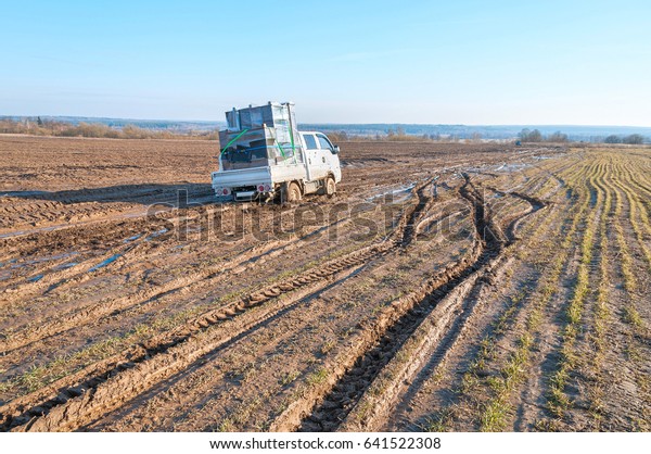 Off-road truck with furniture settles down in mud\
on dirt road in fallow\
field\
