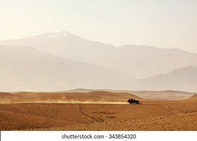 Off-road Vehicle Driving Through Agafay Desert, Morocco, Atlas Mountains Vanishing In Haze