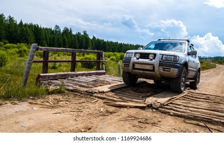 Off-road vehicle on the decayed small wooden bridge on the gravel bumpy road