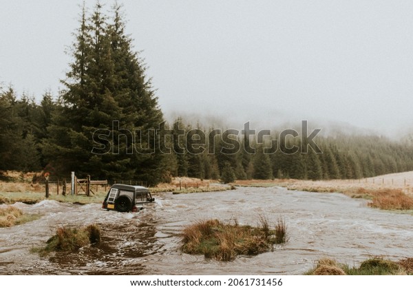 Off-roading car\
stuck in the water stream in\
nature