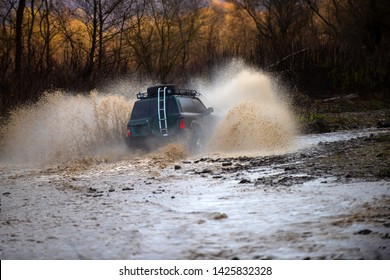 Offroading. Scene Of Wather Splash In Off-road Racing. A Car During A Tough Off-road Competition Diving In A Muddy Pool. Extreme Weekends