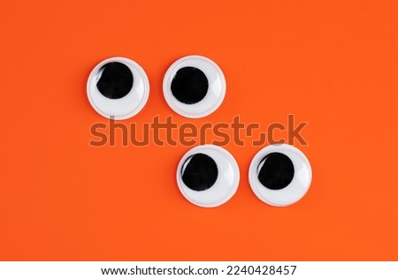 offset pairs of  googly eyes funny Isolated on bright orange background copy space logo