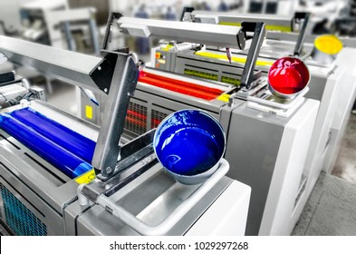 Offset printer press in industry plant. Printing machine print daily newspapers. Detail of four color units, cyan, magenta, yellow and black