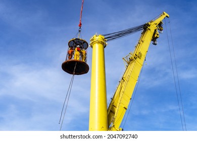 Offshore crews being transferred to a constrution work barge via a personal transfer basket at an oil field
