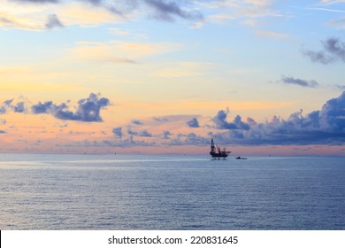 Offshore jack up drilling rig in the middle of the ocean during sunset time