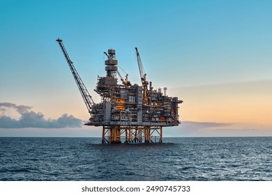 Offshore oil and gas jackup platform in the ocean during beautiful colourful sunset.